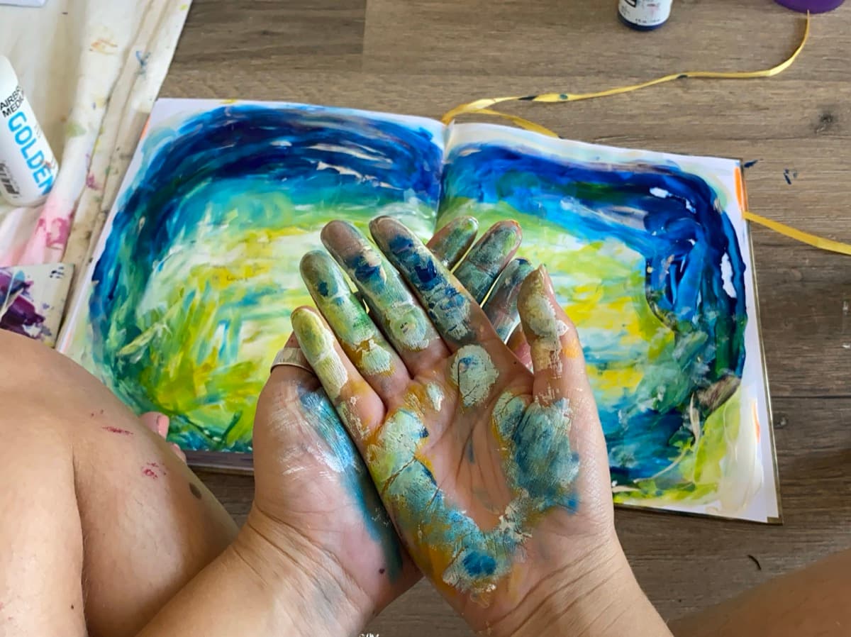 Paint-covered hands over artwork
