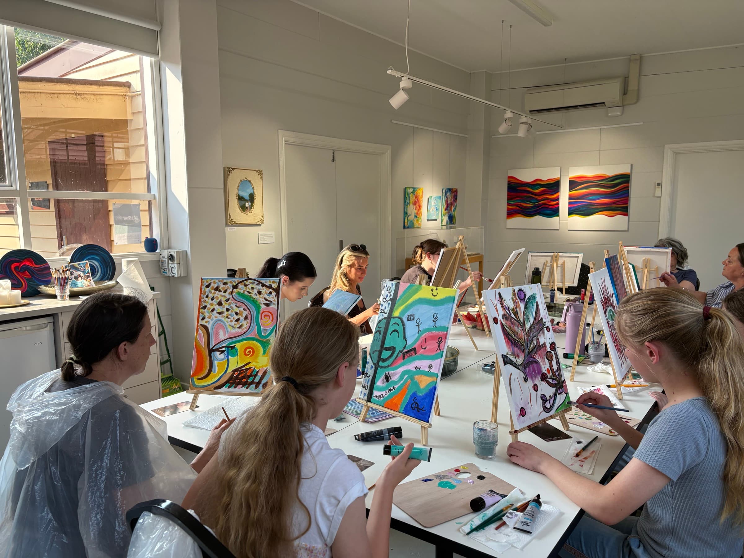 Colorful paintings on easels during a workshop